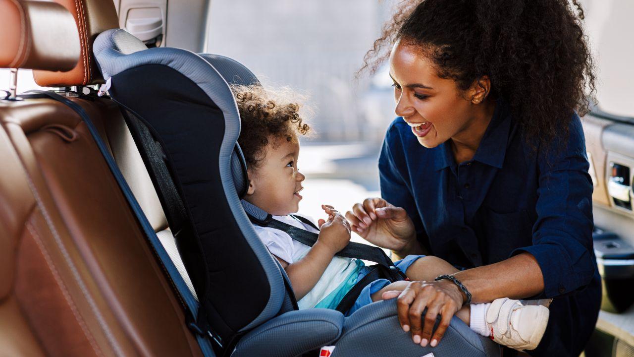 A woman putting a baby in a car seat