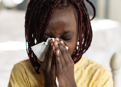 Child sneezing into a tissue