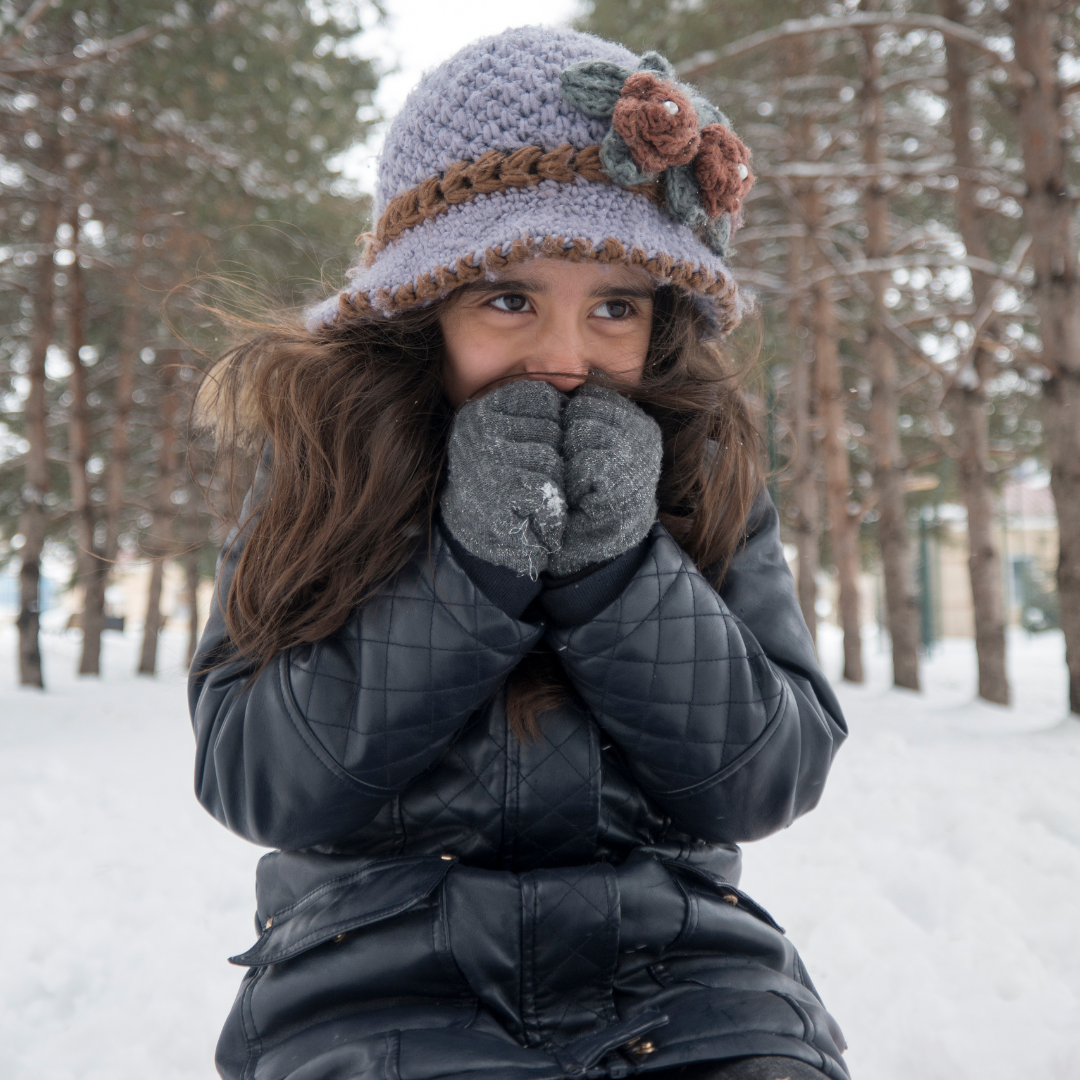 Young girl in a coat and hat shivering in the cold